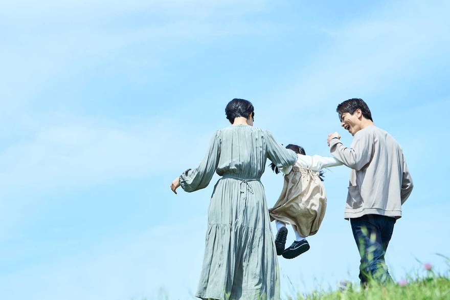 青空の下、草原を歩くご家族