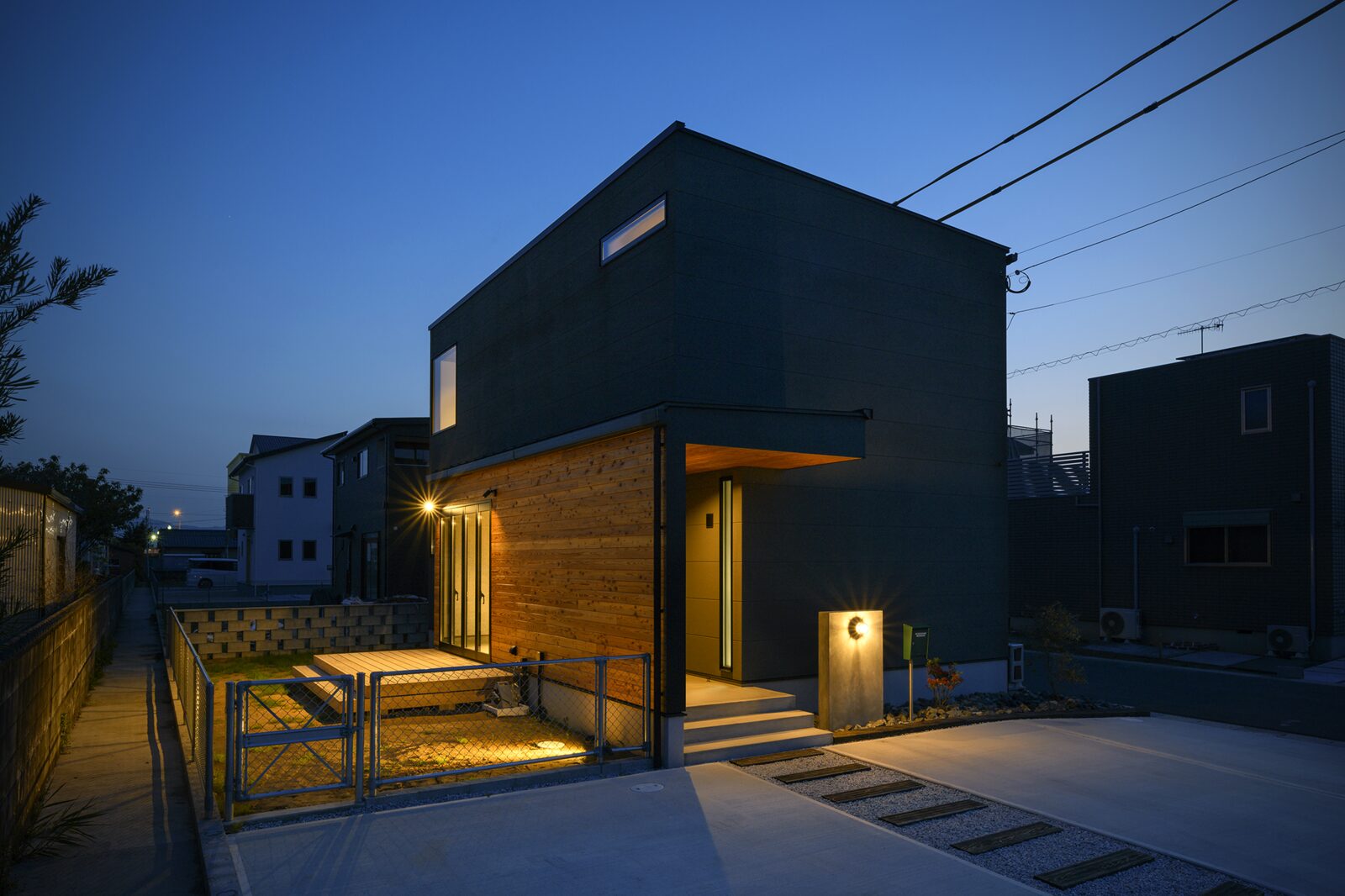 木の玄関まわりが灯る切妻屋根の家の夜景